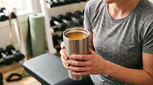 A person holding a steel tumbler of bone broth after a workout as a hydrating recovery drink
